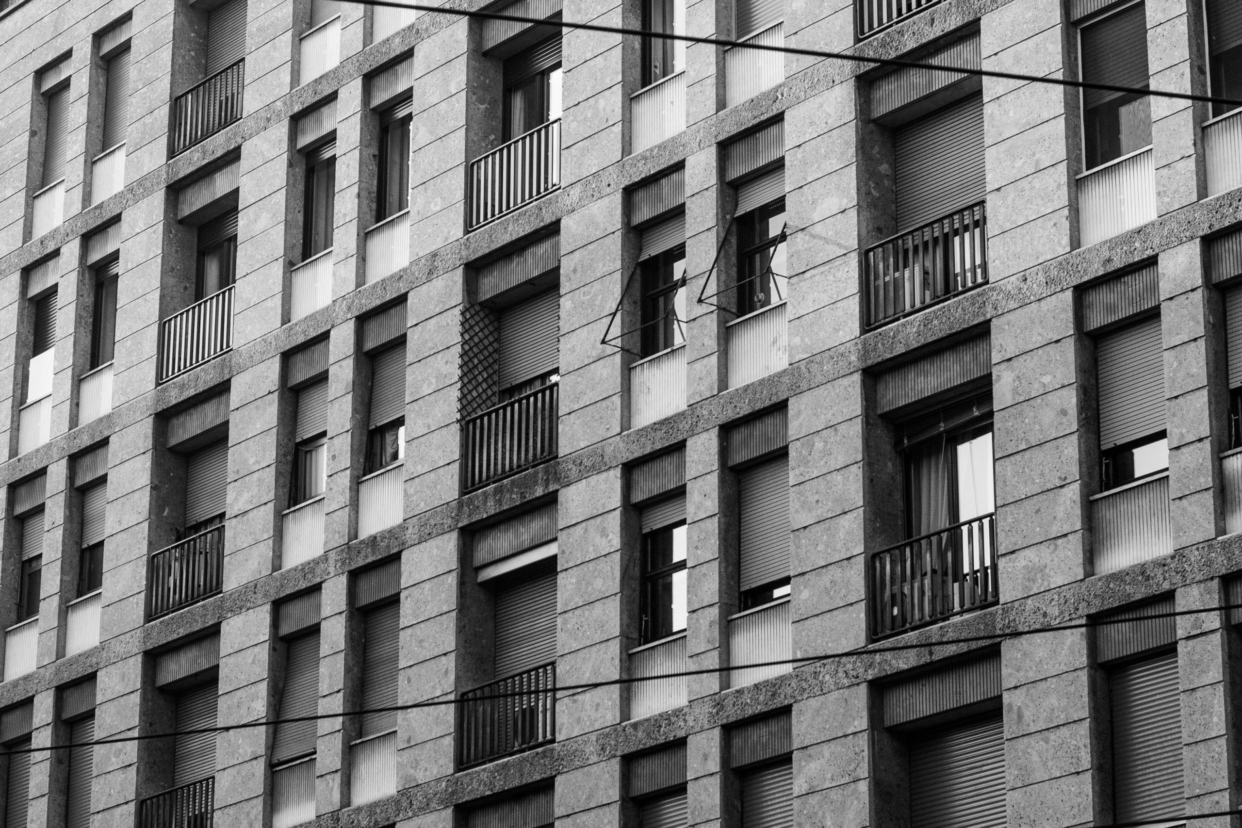 A grayscale shot of a long building with windows and balconies